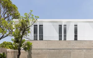 A modern residential building with a minimalist design featuring concrete exteriors and large windows.