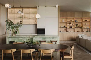 A modern residential kitchen with a marble countertop and wooden furniture.