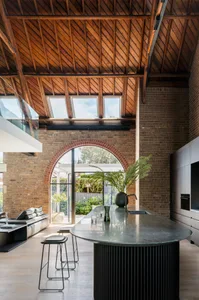 Industrial-style kitchen with brick walls, wooden beams, and concrete countertops.