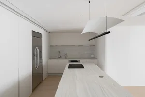 Modern minimalist kitchen interior with white cabinetry and marble countertops.