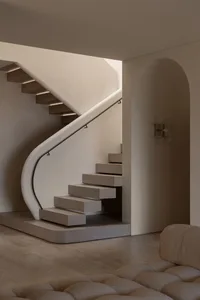 A minimalist staircase with wooden steps and a concrete wall, featuring a modern railing and a well-lit space.