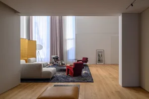 Modern living room featuring wooden flooring, a comfortable sofa, and cozy armchairs.
