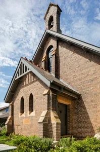 Traditional church building constructed of brick with a clock tower and bell.