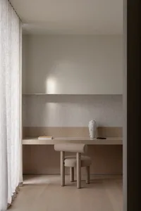 Photograph of a minimalist bedroom featuring wooden furniture and a white vase.