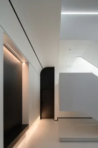 A minimalist design corridor featuring white walls and floors, with subtle lighting and a sleek, modern aesthetic.
