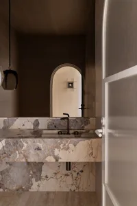 A modern bathroom with a marble countertop and an arch-shaped window.