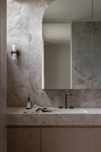 Modern bathroom with marble walls and floor, featuring a sleek countertop and minimalist design.