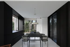 Modern black kitchen and dining room interior with dark wood accents.