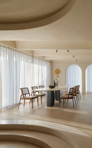 A modern dining room featuring a wooden dining table and chairs, with large windows and a warm, neutral color palette.