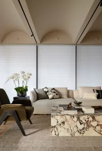 A modern living room featuring a sofa upholstered in fabric and velvet, with a marble coffee table and floor-to-ceiling windo