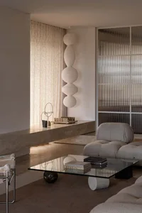 A minimalist living room featuring glass, marble, and fabric materials.