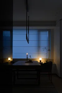 A serene living space with textured blue walls and soft lighting, featuring a candle and small green plant.