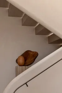A modern, minimalist staircase featuring wooden sculptures as decorative elements.