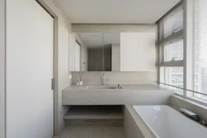 Modern minimalist bathroom featuring concrete tiling, double sinks, and a freestanding bathtub with white blinds and a large 