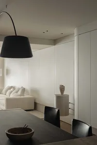 A minimalist dining room features white cabinets and black furniture, creating a modern and sleek ambiance.