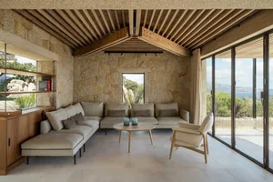 A minimalist residential interior featuring stone, wood, and glass materials.