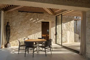 Modern dining room with stone walls, wood accents, and glass windows.