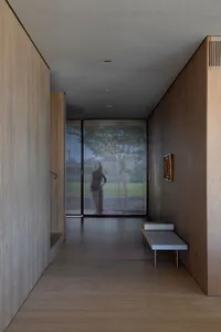 A modern hallway with wood walls and a glass panel at the end.