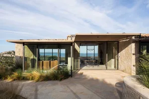 Modern residential building featuring large glass windows and stone walls.