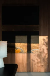 A modern interior design featuring abstract art with stark lines and warm tones against wooden panels.