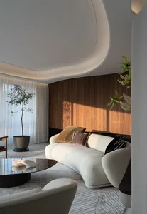 Modern living room with white leather couch, wooden walls, and glass table with pebbles.