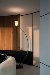 A modern, minimalist living room featuring a sleek metal floor lamp with a curved design.