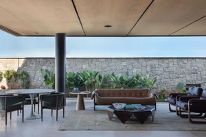 Modern living room with wooden ceiling, concrete walls, and leather furniture.
