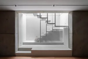 A minimalist white concrete interior space with geometric architectural elements.