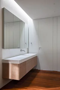 Modern minimalist bathroom with white marble countertop and warm wood accents.