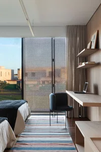 Modern minimalist bedroom featuring wooden furniture on striped rug