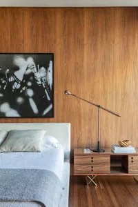 A modern bedroom features a clean, minimalist design with a large bed, wooden nightstand, and wooden walls.