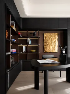 A modern black office with dark wood finishes and a gold abstract wall art piece.
