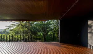 Modern interior space featuring wooden flooring and glass windows overlooking greenery.