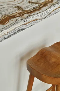 A modern interior design featuring a wooden stool and marble countertop.
