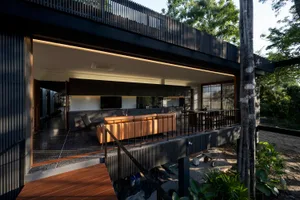 A modern residential outdoor living space featuring wooden flooring, metal railings, and concrete elements.