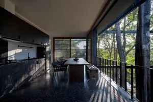 Modern kitchen with black countertops and stainless steel appliances, granite countertops, and a view of the forest through l
