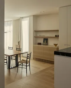 Modern minimalist residential interior featuring wooden furniture, marble countertops, and glass elements.