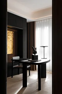 A modern home office featuring a black wooden desk with a rabbit sculpture and a lamp.