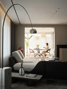 A modern, minimalist living room with a white sofa, black coffee table, and floor-to-ceiling windows.