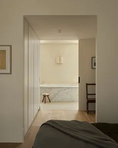 Modern minimalist bedroom with a marble bathtub in the background.