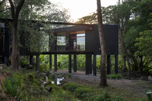 Modern dark wood exterior residential architecture with individuals standing on a veranda.