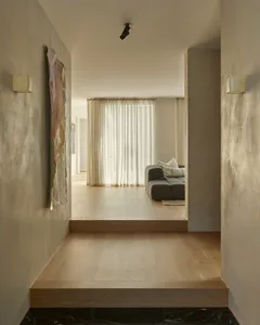 Modern living room with clean lines, featuring a gray sectional sofa, light wooden floors, and sheer curtains.