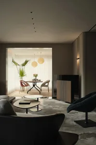 A modern living room with a contemporary design, featuring a neutral-color leather sofa, a glass coffee table, and ambient li