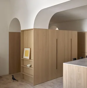 Modern minimalist kitchen featuring light wood cabinets and shelves, with a yellow circular art piece and a black bird figuri