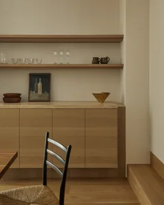 A modern Scandinavian kitchen featuring sleek wooden storage units adorned with minimalist decorative items.