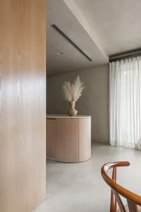 A minimalist living room with wooden furniture and a vase of dried plants.