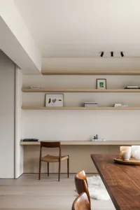 A modern dining room featuring minimalist design principles with wooden furnishings and open shelving.