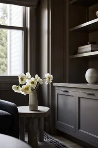 A modern living room with a grey concrete cabinet featuring white flowers in a vase.