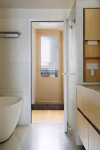 A minimalist bathroom with white tiled walls and wooden accents.