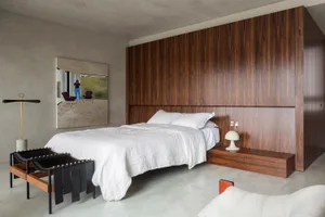 A minimalist bedroom featuring a bed with a wooden headboard and white bedding.